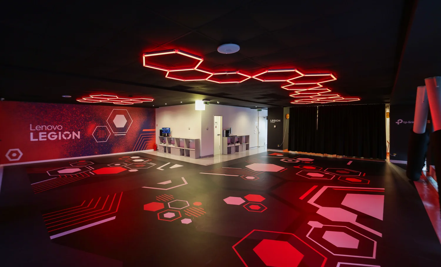 Sala Gateway Flow în configurație cu podea liberă: spațiu deschis, fără mobilier, cu iluminat hexagonal roșu în tavan și grafică aplicată pe pardoseală.